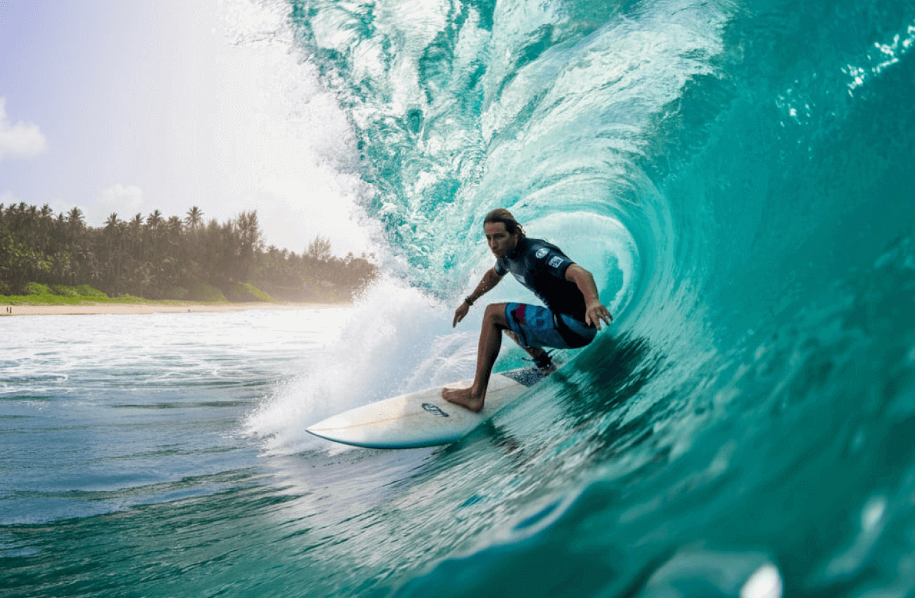 A surfer riding a wave in the clear water just off a Koh Phangan beach